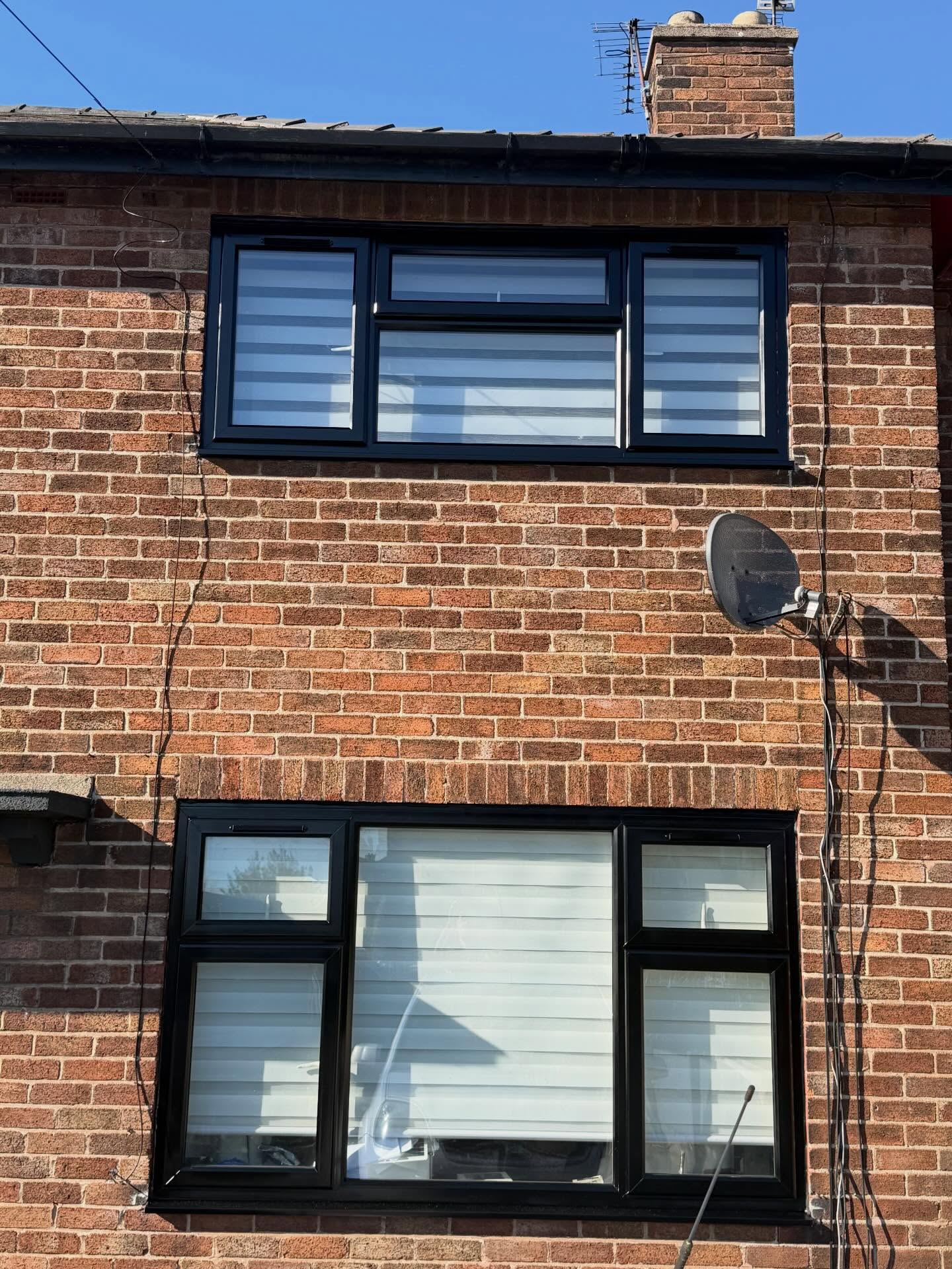 House elevation with uPVC windows and downpipes resprayed jet black by The Northwest Spray Co.