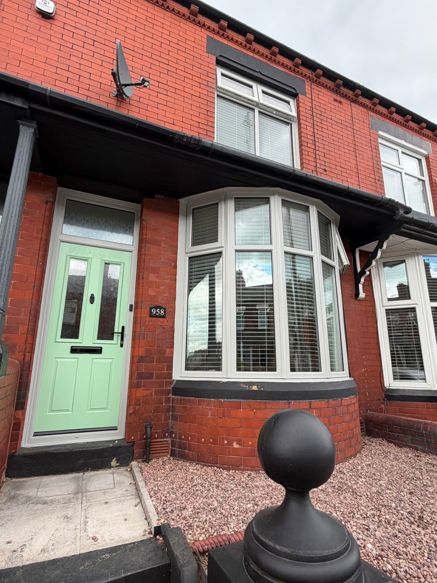 Red brick terrace with a front door resprayed green and bay window frames sprayed cream.