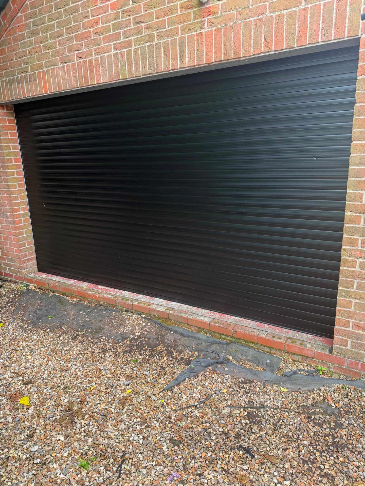The same roller garage door resprayed jet black with an even factory-quality finish.