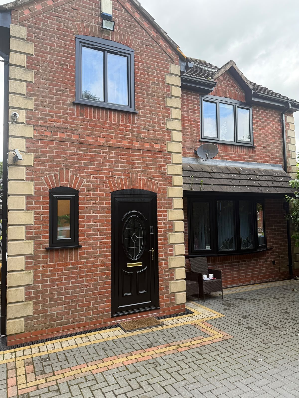 The same uPVC front door, bay window and casements resprayed jet black with a smooth factory-quality finish.