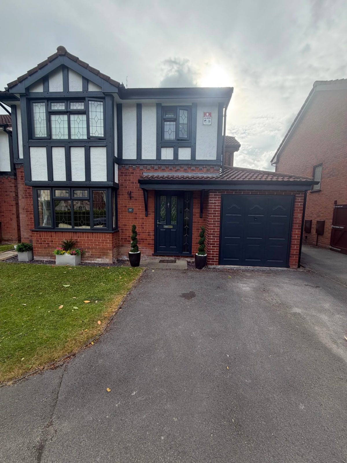 Detached Tudor-style home with beams, windows, front door and garage door resprayed anthracite grey.