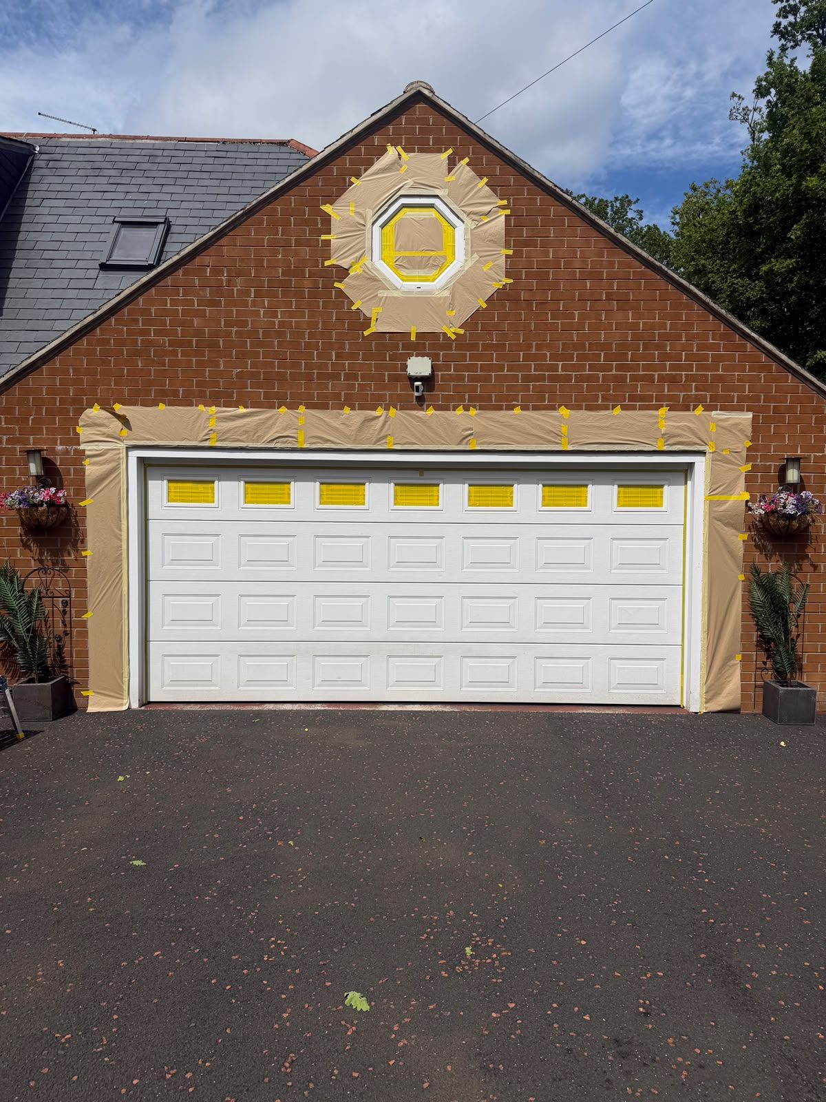 White double garage door and octagonal window masked and prepared for spraying.